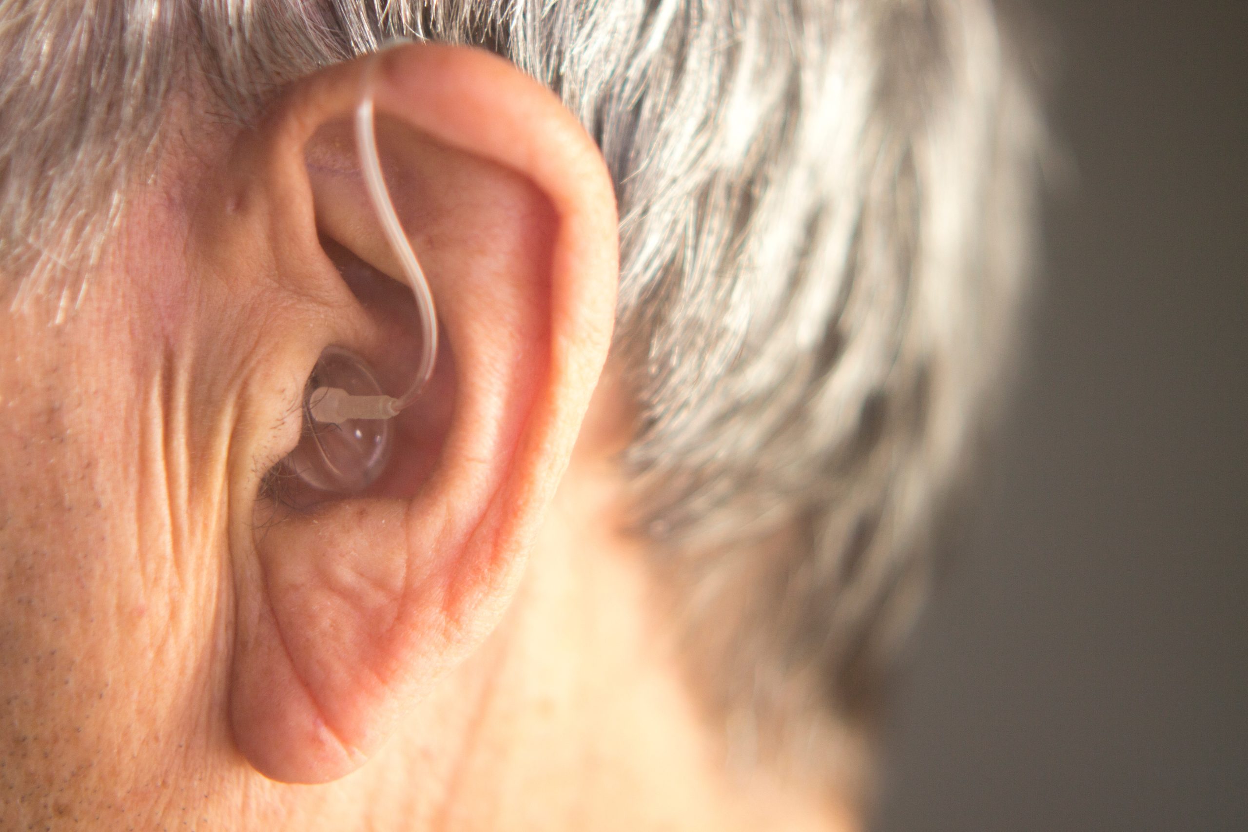 Digital modern hearing aid in the ear of aged old man.